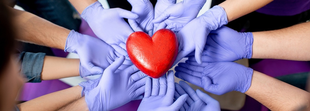 Groep handen van mensen met handschoenen aan dragen een hart