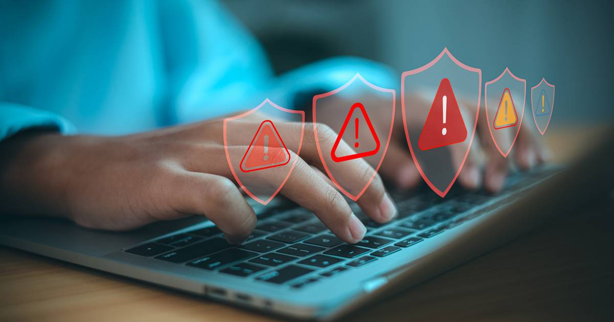 Man achter laptop krijgt alert meldingen met de icoontjes van rode driehoeken en uitroeptekens