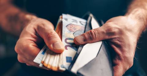 Man met een portemonnee in zijn hand gevuld met geld 